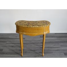 an old wooden table with a marble top and curved legs, sitting on a wood floor