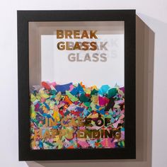 an art piece is displayed in a frame with the words break glass on it, surrounded by confetti