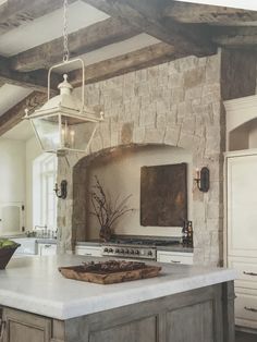 a kitchen with an island, stove and large lantern hanging over it's head