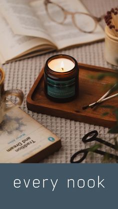 a candle sitting on top of a wooden tray next to a book and eyeglasses