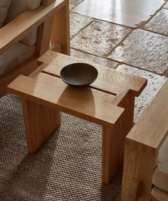 a bowl sitting on top of a wooden table next to a bench and chair in a living room