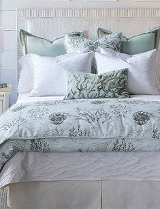 a bed with white and green comforters in a bedroom next to two nightstands