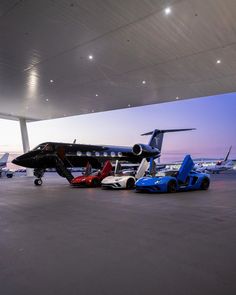 several different colored sports cars parked in front of an airplane