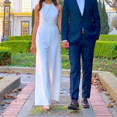 a man and woman in formal wear walking down a sidewalk holding hands with each other