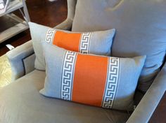 two orange and gray pillows sitting on top of a chair