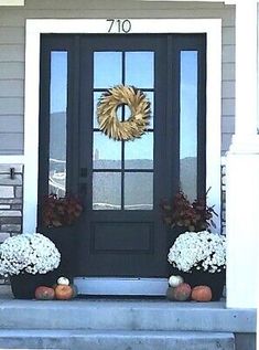 the front door is decorated with flowers and pumpkins