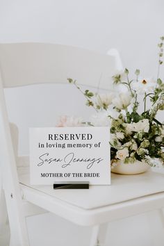 a white table with flowers and a sign on it that says reserved in loving memory of susan young, mother of the bride