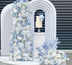 a white and blue wedding cake on top of a table next to a vase with flowers