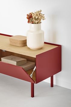 a table with a flower pot on it and a book in the bottom drawer next to it