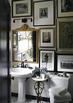 a bathroom with pictures on the wall and a pedestal sink