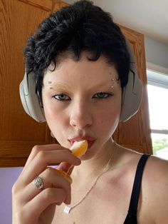 a woman wearing headphones and eating an orange