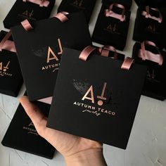 a person holding up some black boxes with pink ribbons on them and the letters autumn written in gold