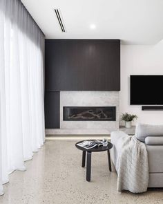 a living room with a couch, coffee table and television mounted on the wall above it