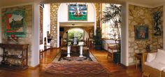 a living room filled with lots of furniture next to a stone wall and arched doorway