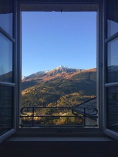 an open window with mountains in the background