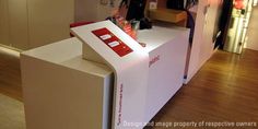 a white counter with red and white signs on it in front of a store window