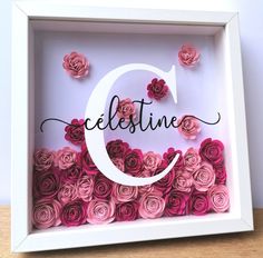 a white frame filled with pink roses and the letter c