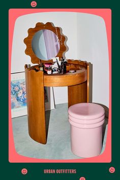 a wooden vanity table with a mirror and pink trash can