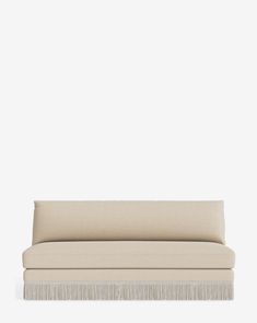 a beige couch with fringes on the bottom and back end, against a white background