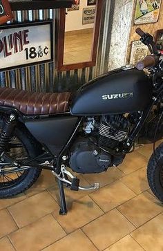 a black motorcycle parked in front of a sign and some other items on the wall