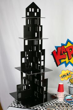 a tall black tower sitting on top of a table next to a red and white cone