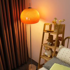 an orange floor lamp next to a bed in a room with curtains and a book shelf