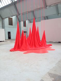 an art installation with red plastic cones suspended from the ceiling and dripping paint on the floor