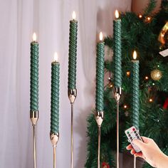 a person is holding a remote control in front of some candles and a christmas tree