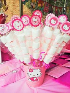 there are hello kitty candy sticks in a cup on the table with pink tissue paper