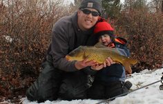 a man kneeling down next to a child holding a fish