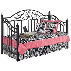 a black metal bed with pink and zebra print bedspread, pillows and laptop on it