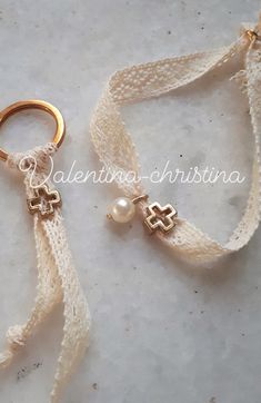 two gold - plated rings with pearls are sitting on a white fabric strap that is tied to the floor