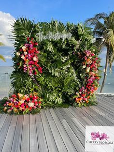 the wedding sign is decorated with flowers and greenery on top of a wooden deck