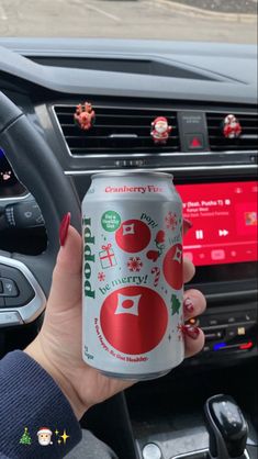 a woman holding up a can of soda in her car