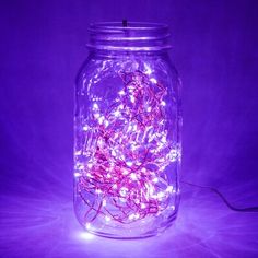 a mason jar filled with fairy lights on a purple background