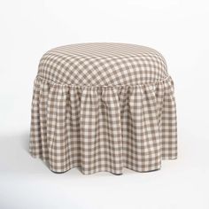 a brown and white checkered ottoman with a ruffled skirt on the bottom, sitting in front of a white background