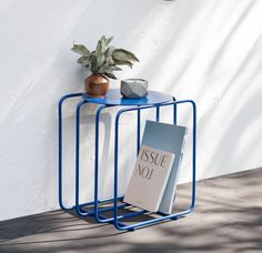 a blue table with a book on it and a potted plant next to it