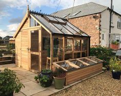 a small wooden building sitting in the middle of a yard with potted plants around it