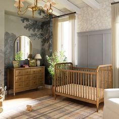 a baby's room with a crib, dresser and mirror on the wall