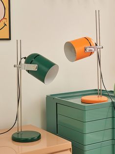 an orange and green desk lamp sitting on top of a table next to a dresser