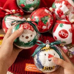 someone is holding christmas ornaments in their hand and they are decorated with snowman faces