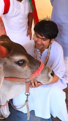 a man kneeling down next to a cow