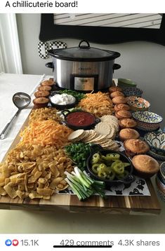 a wooden cutting board topped with different types of food next to a crock pot