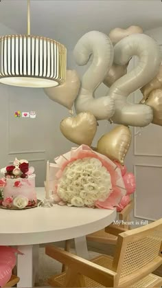 a table topped with a cake and lots of balloons