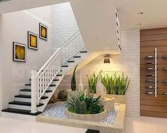 a white staircase with plants and pictures on the wall