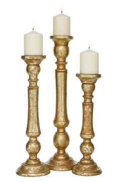 two gold candlesticks with white candles on them