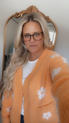 a woman wearing glasses taking a selfie in front of a mirror with her hand on her hip