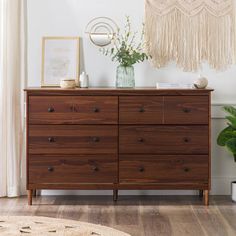 a wooden dresser sitting in a living room next to a potted plant on top of a rug