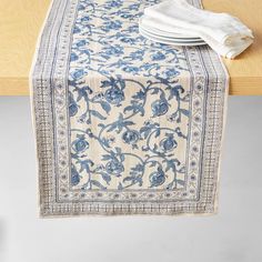 a blue and white table runner sitting on top of a wooden table