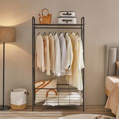 an iron rack with clothes hanging on it in a bedroom next to a bed and lamp